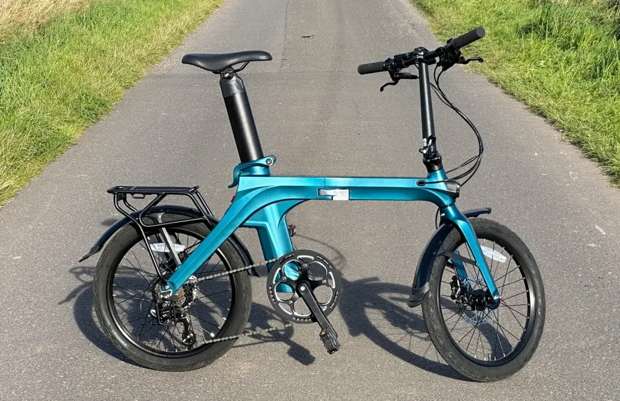 Vélo pliant turquoise Fiido X v2 sur une route asphaltée, prêt pour une balade.