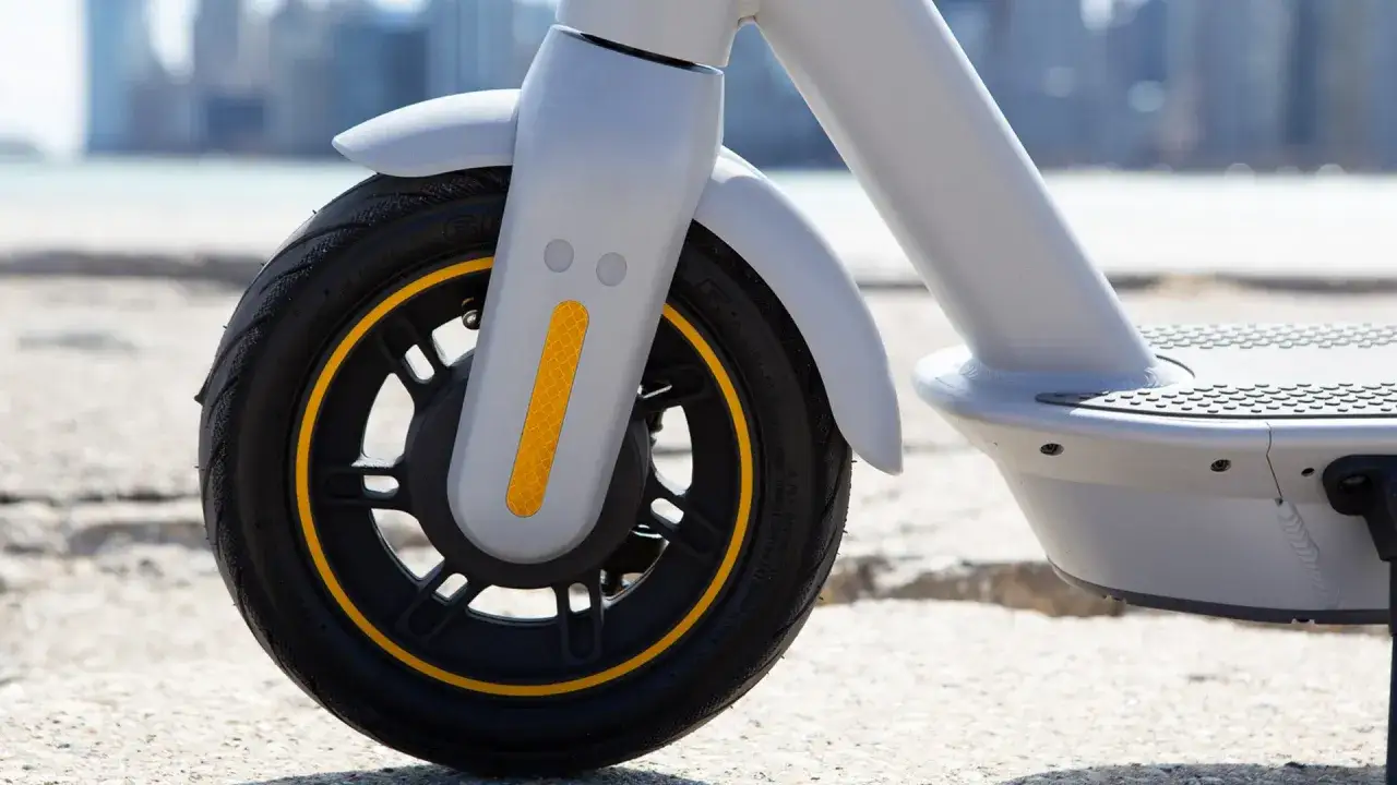 Gros plan sur la roue avant d'un Ninebot G30 Max, avec le pneu noir et sa bande jaune. La pression pneu Ninebot G30 Max est essentielle pour une conduite optimale.