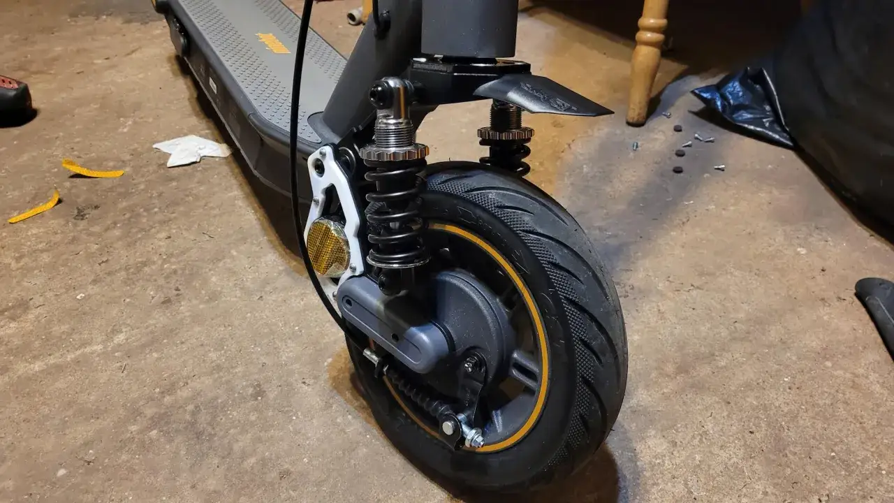 Le pneu arrière d'un trottinette électrique, avec son amortisseur et son garde-boue, prêt pour de nouvelles aventures. Le mot