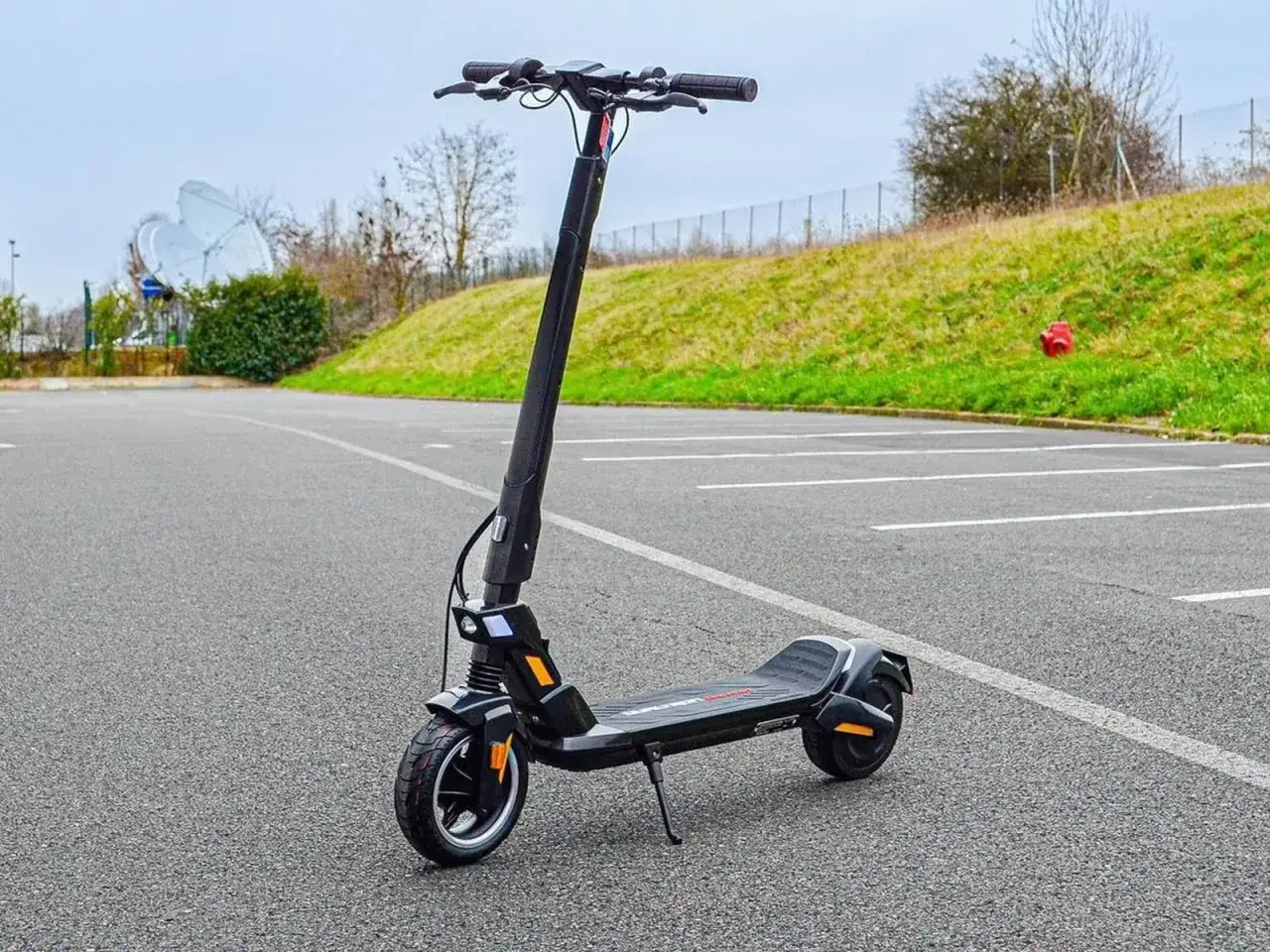 Trottinette électrique Dualtron Togo noire, prête à l'aventure sur un parking désert.