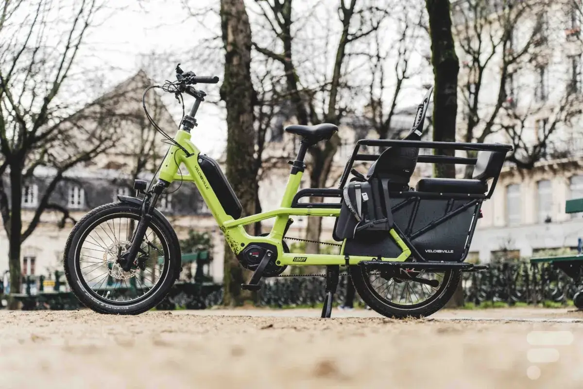 Vélo électrique vert vif, prêt pour le transport de charge lourde, avec siège enfant intégré.