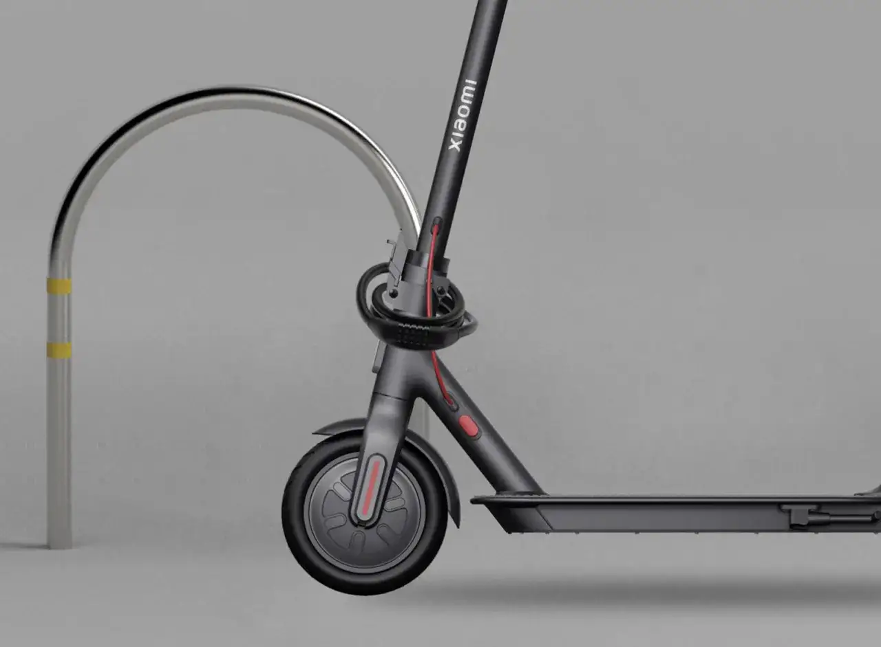 Trottinette électrique Xiaomi sécurisée par un antivol intégré, attachée à un arceau métallique.