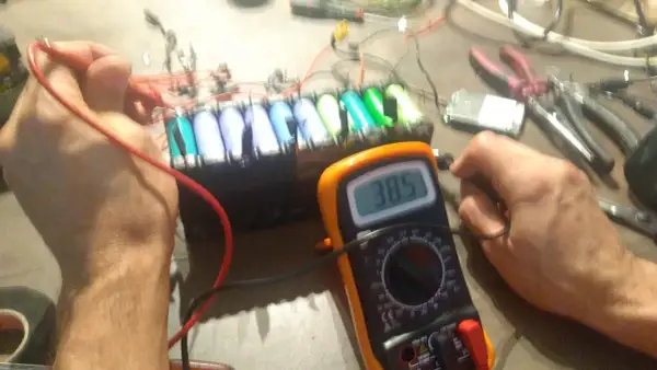 Diagnostic d'un **problème batterie** sur une **draisienne Moovway**. Un multimètre affiche 38.5V, mesurant la tension d'un pack d'accus.