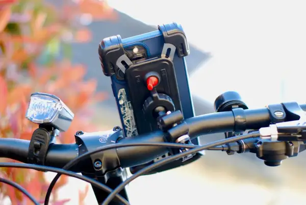 Support téléphone trottinette action : un smartphone est fixé sur le guidon, prêt pour l'aventure.