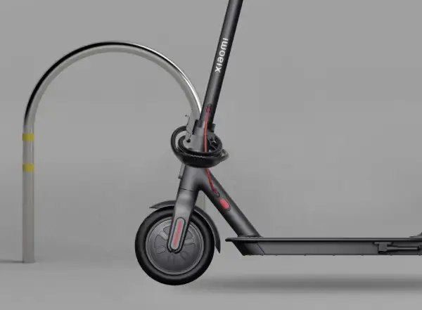 Trottinette électrique Xiaomi sécurisée par un antivol intégré, attachée à un arceau métallique.