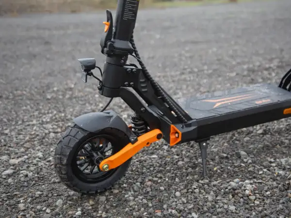 Gros plan sur la roue avant d'une trottinette électrique, dotée d'un pneu 8 pouces tout-terrain et d'une suspension orange vif.