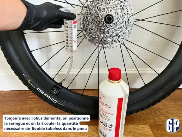 Maintenant, découvrez comment mettre liquide préventif tubeless : une seringue injecte le produit dans le pneu de vélo, à côté d'une bouteille de liquide.