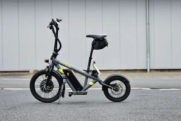 Draisienne électrique pliante grise, prête pour l'aventure urbaine.
