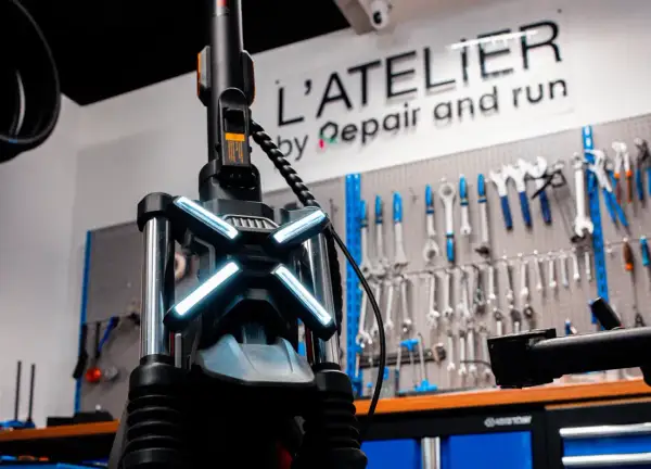 Le guidon d'une trottinette électrique avec ses feux lumineux, prêt pour une réparation à l'atelier.
