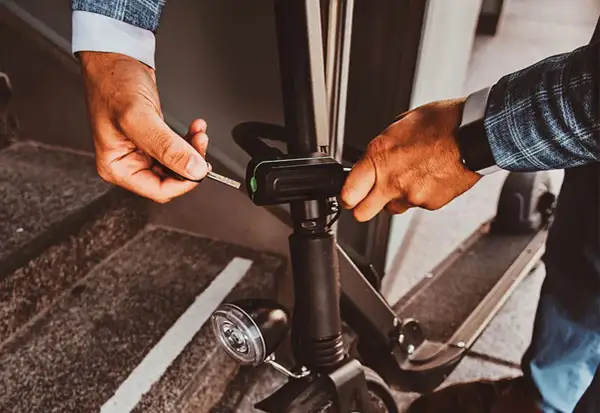 Un homme utilise une clé pour activer l'antivol de sa trottinette électrique, assurant ainsi sa sécurité.