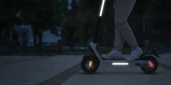 Une trottinette électrique avec une bande réfléchissante sur le guidon et le plateau, pour une visibilité accrue la nuit.