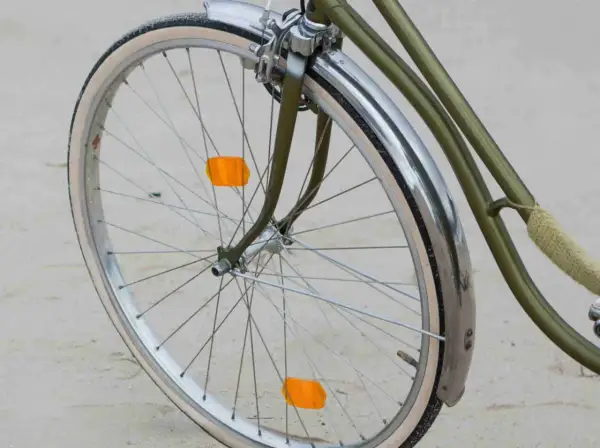 Roue de vélo verte avec garde-boue chromé et deux catadioptres orange pour la sécurité.